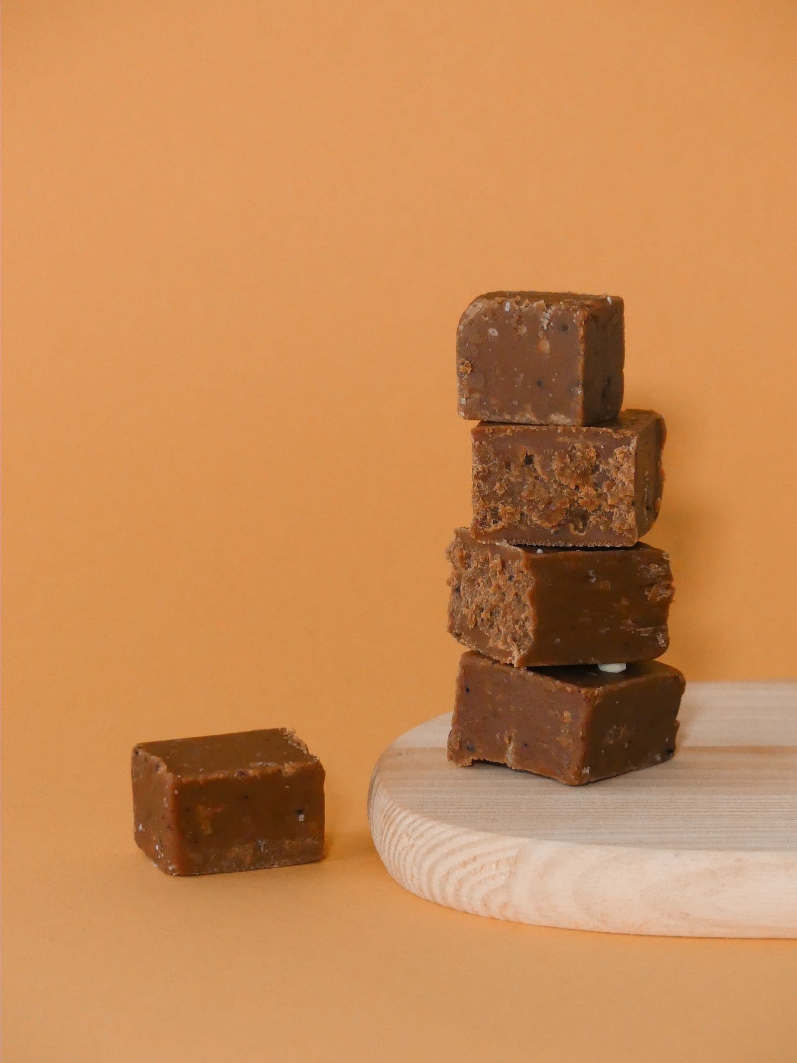 Squares of hand-cut fudge stacked on a wooden board