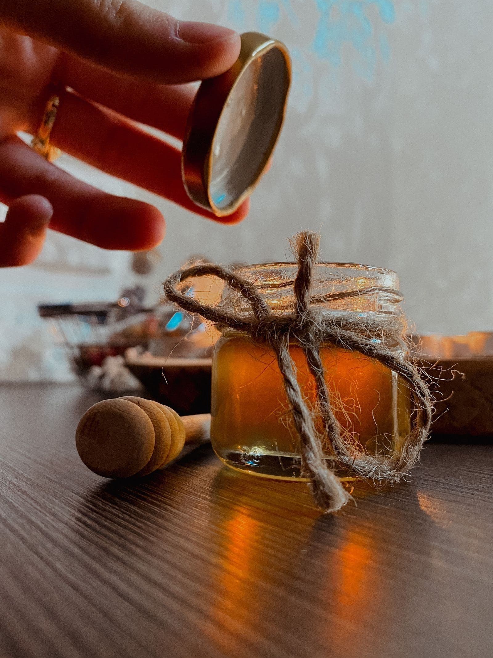 Honey being drizzled over a jar tied with twine