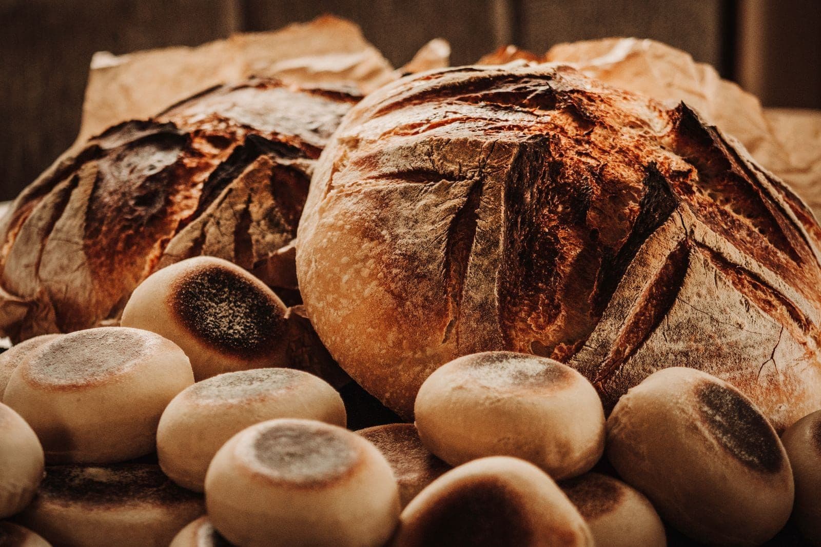 A batch of dark-baked loaves and rolls, flour still on the crust