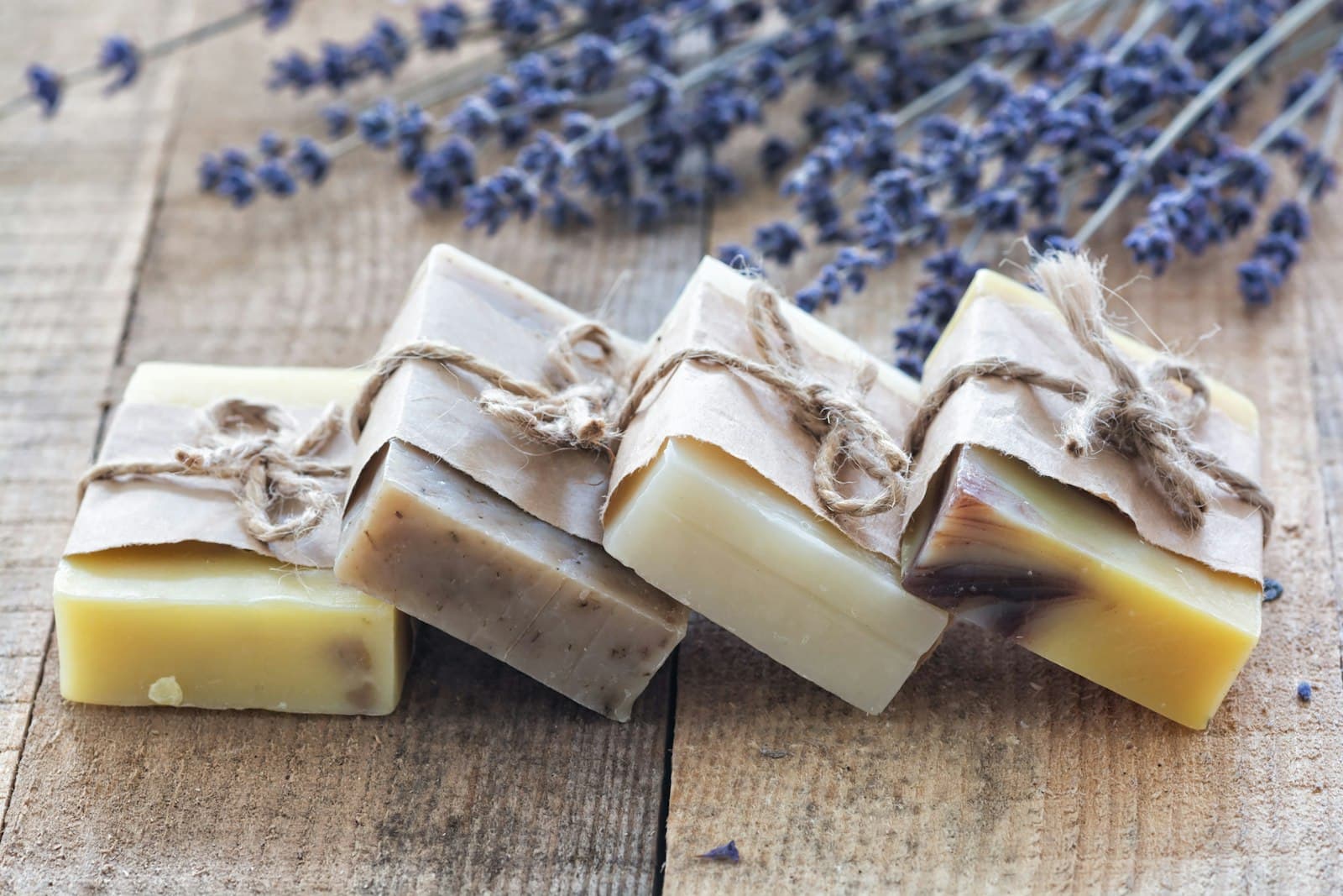 Hand-milled soap bars wrapped in paper and tied with twine, lavender alongside
