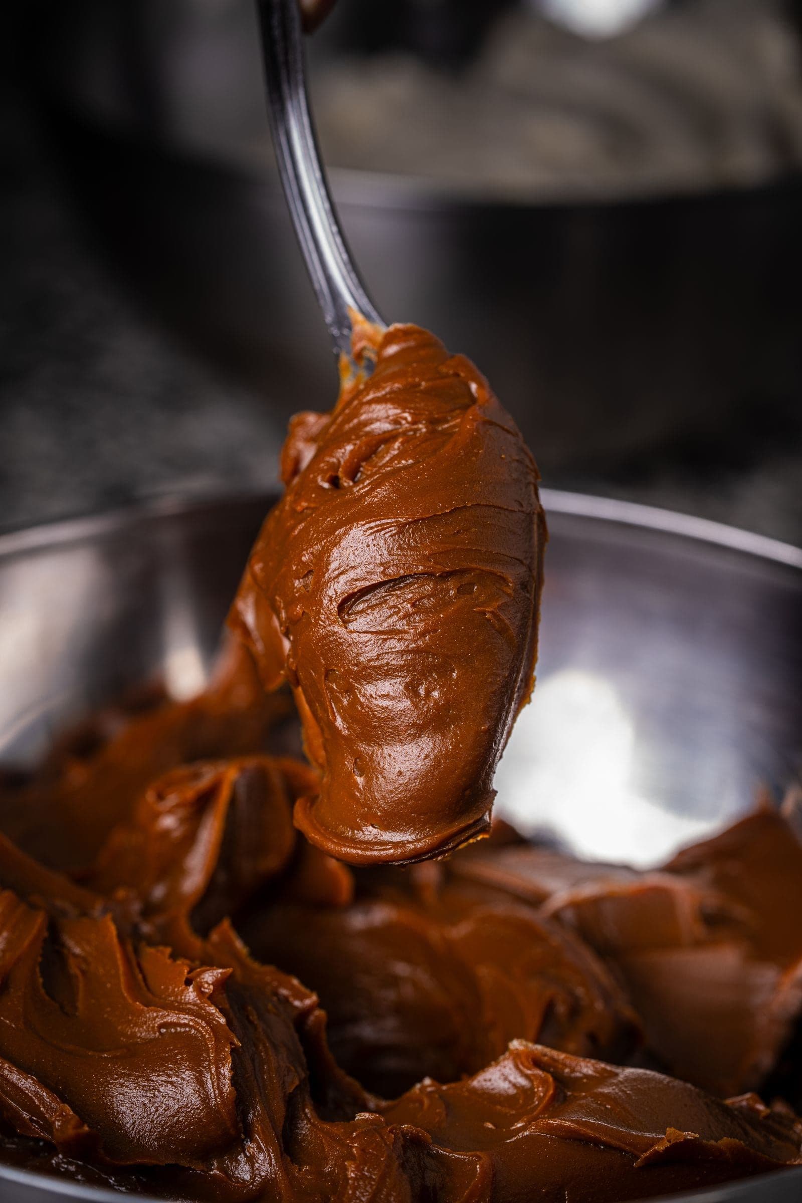 Glossy chocolate being worked in the bowl mid-temper