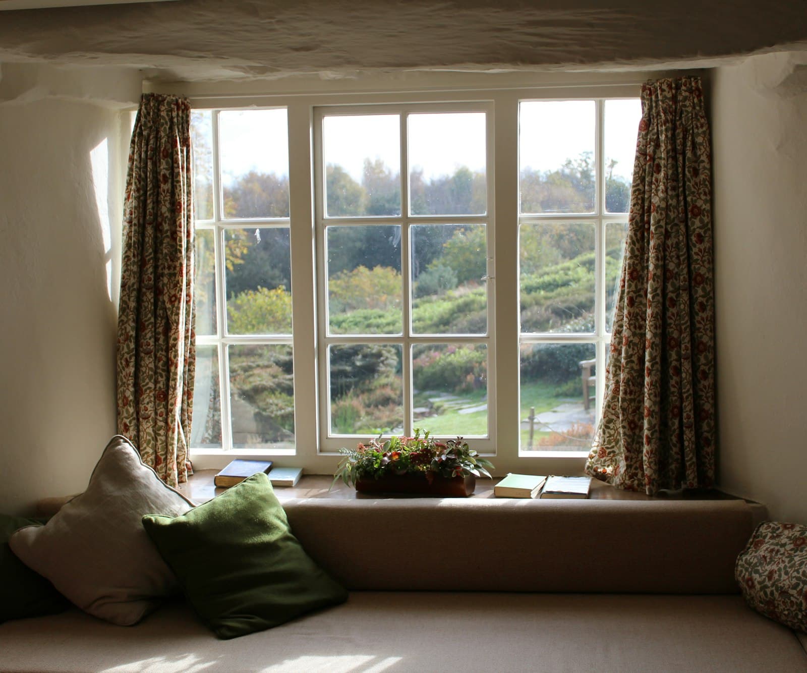 A sunlit cottage window seat looking onto an English garden