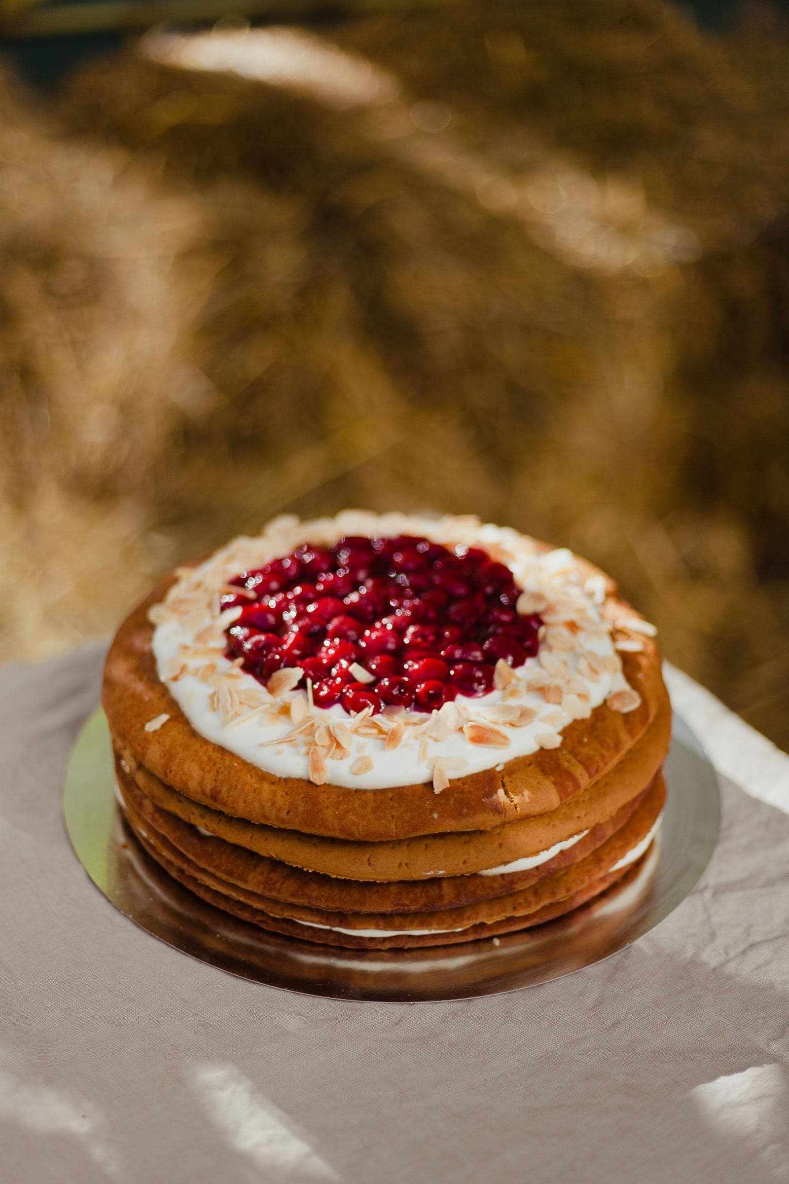 A cream-layered cake topped with pomegranate and flaked almonds